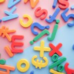 a pile of plastic letters and numbers on a pink and blue background