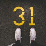 person standing beside 31 painted gray concrete road at daytime