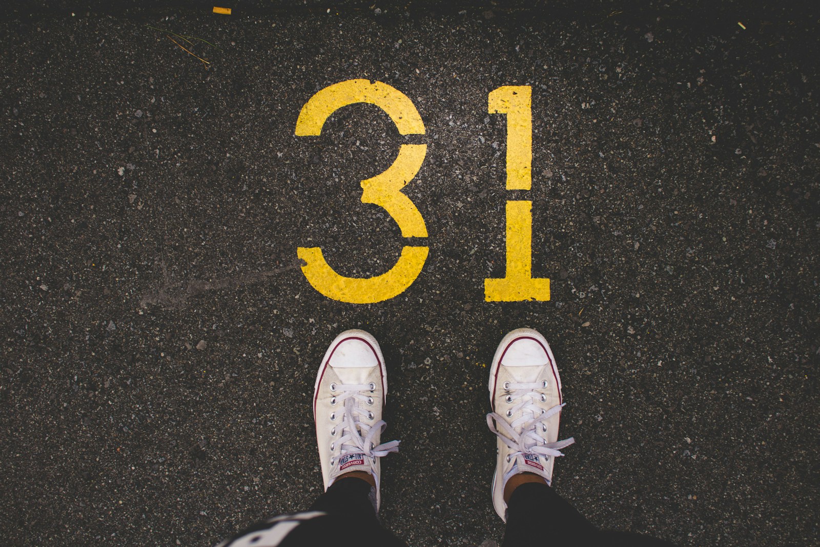 person standing beside 31 painted gray concrete road at daytime